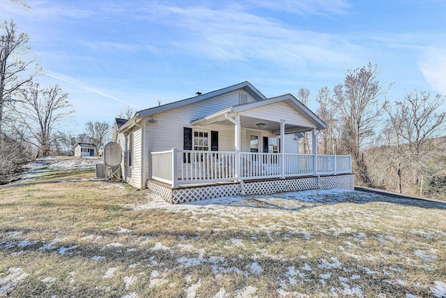 view of front facade featuring covered porch, a front lawn, and cooling unit