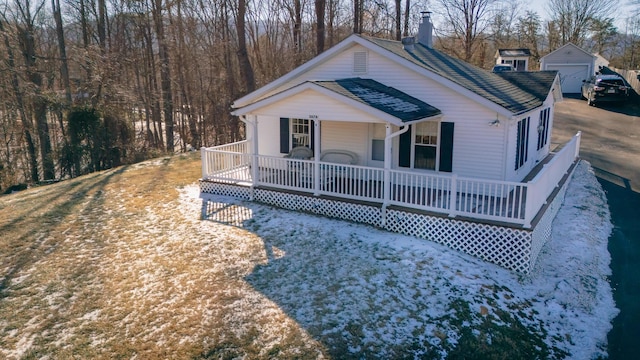 view of front facade with a garage, a porch, and an outbuilding