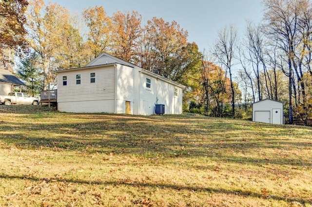 view of side of property featuring central air condition unit, an outbuilding, a yard, a wooden deck, and a garage