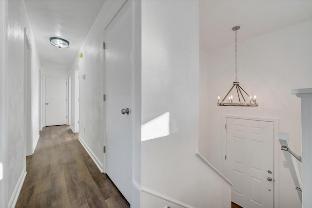 corridor featuring a notable chandelier and dark wood-type flooring