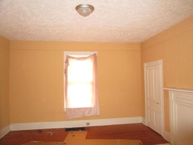 unfurnished room with a textured ceiling and hardwood / wood-style flooring