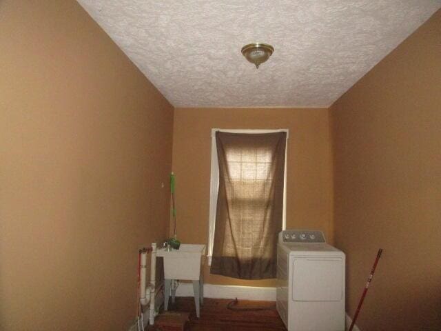 clothes washing area featuring hardwood / wood-style flooring, a textured ceiling, and washer / clothes dryer