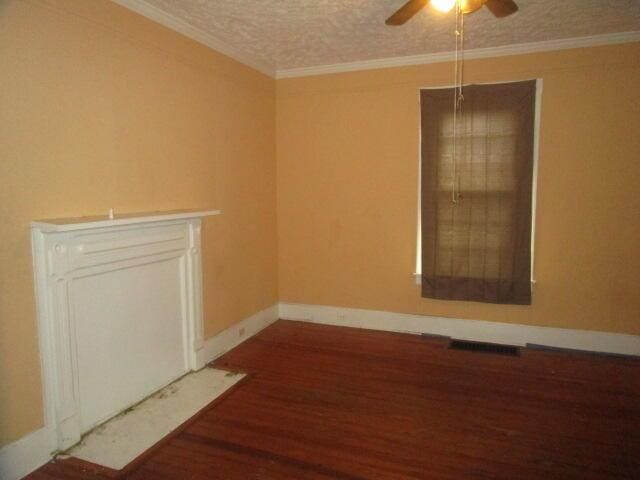 empty room with wood-type flooring, a textured ceiling, ceiling fan, and crown molding