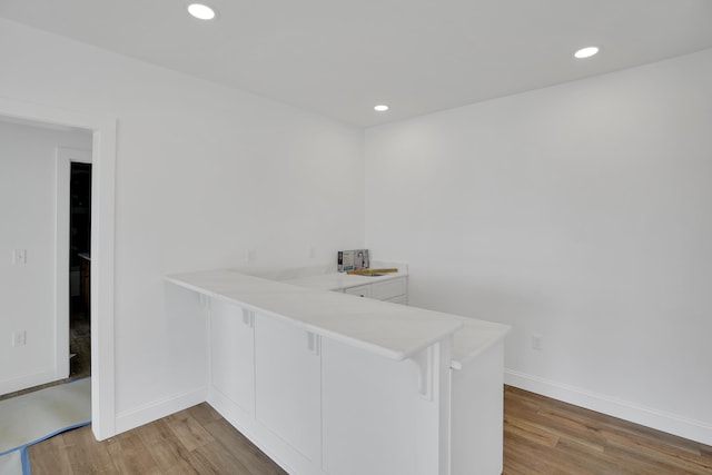 bar featuring white cabinetry, wood-type flooring, and sink