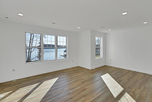 unfurnished room featuring a water view and light hardwood / wood-style flooring