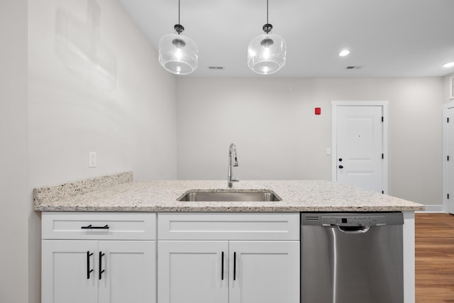 kitchen with light stone countertops, sink, white cabinets, and stainless steel dishwasher