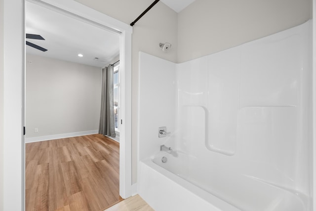 bathroom with hardwood / wood-style floors, ceiling fan, and bathtub / shower combination