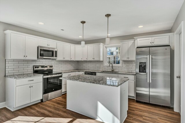 kitchen with decorative light fixtures, white cabinets, appliances with stainless steel finishes, and sink