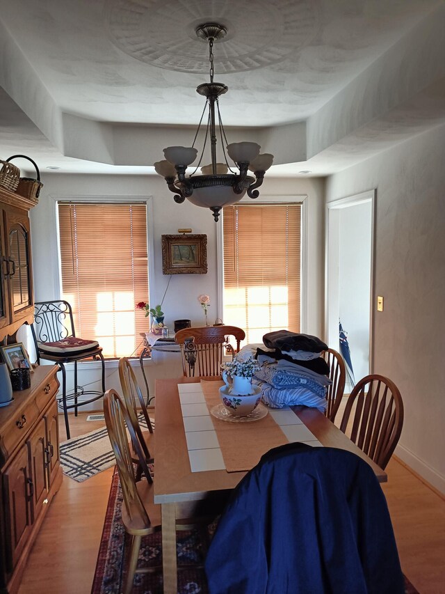 dining area with a wealth of natural light, light hardwood / wood-style flooring, and a chandelier