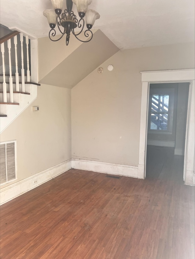 unfurnished living room featuring dark wood-type flooring, vaulted ceiling, and a chandelier