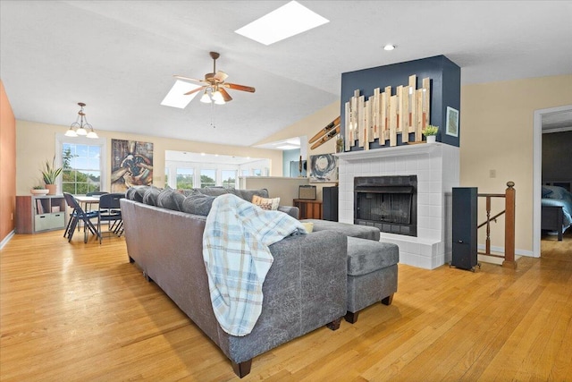 living room with lofted ceiling, hardwood / wood-style floors, ceiling fan, and a tile fireplace