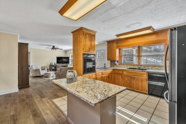 kitchen featuring sink, ceiling fan, light hardwood / wood-style floors, decorative backsplash, and black appliances