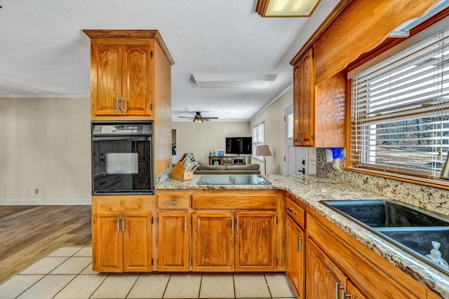 kitchen with light tile patterned floors, a textured ceiling, black appliances, and ceiling fan