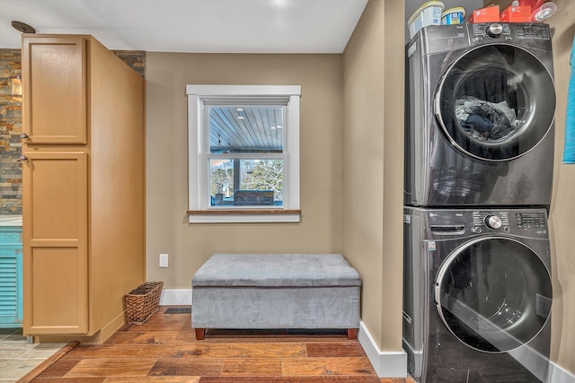 clothes washing area with cabinets, stacked washer and clothes dryer, and dark hardwood / wood-style floors