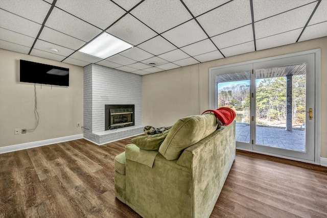 living room featuring hardwood / wood-style floors, a drop ceiling, and a fireplace