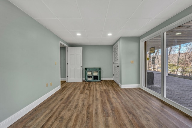 unfurnished living room with wood-type flooring and a paneled ceiling