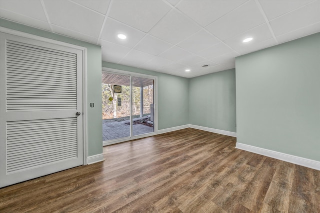 empty room featuring a paneled ceiling and dark hardwood / wood-style floors