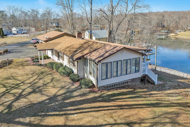 view of side of property featuring a water view, a sunroom, and a lawn