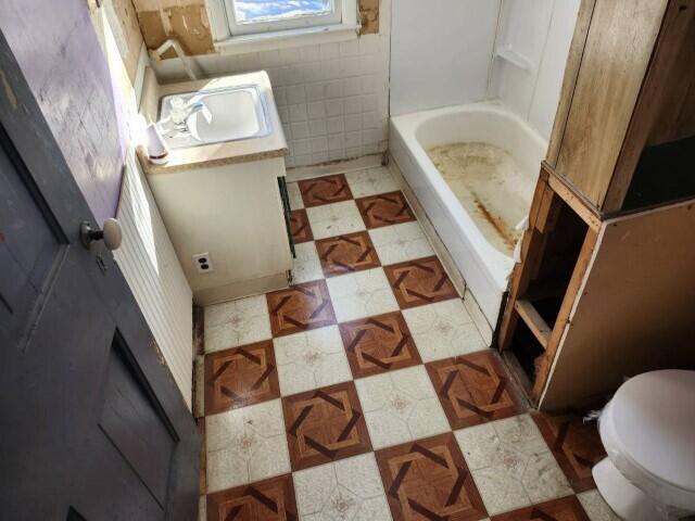 bathroom featuring tile walls, toilet, and vanity