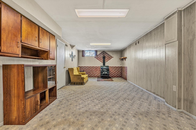 unfurnished room featuring a wood stove, light colored carpet, and wood walls