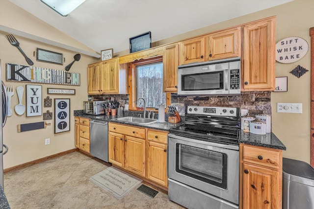 kitchen featuring appliances with stainless steel finishes, decorative backsplash, dark stone countertops, vaulted ceiling, and sink