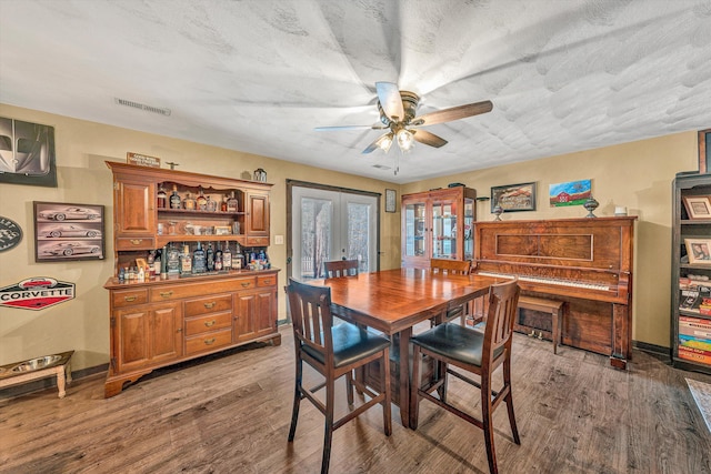 dining room featuring ceiling fan, french doors, dark hardwood / wood-style flooring, and a textured ceiling