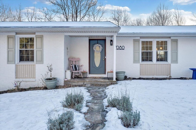 snow covered property entrance featuring covered porch