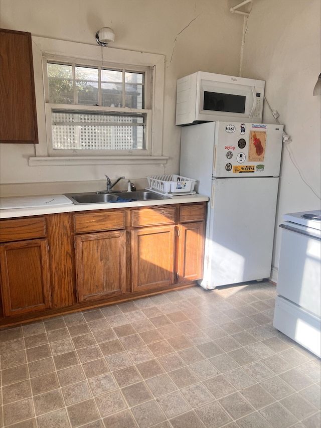 kitchen with sink, white appliances, and decorative light fixtures