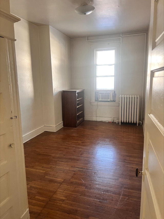 empty room featuring cooling unit, radiator, and dark hardwood / wood-style flooring