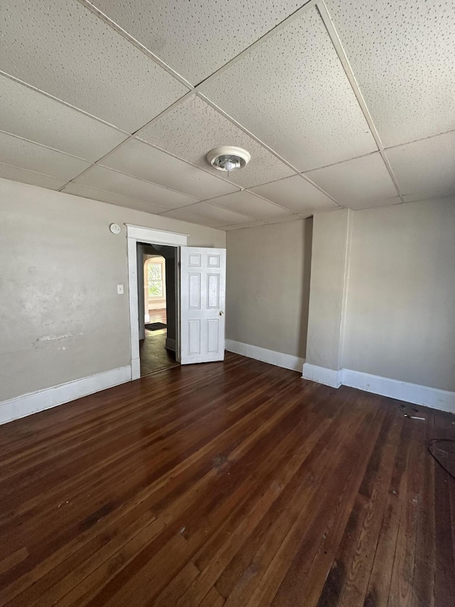 empty room featuring a paneled ceiling and dark hardwood / wood-style floors