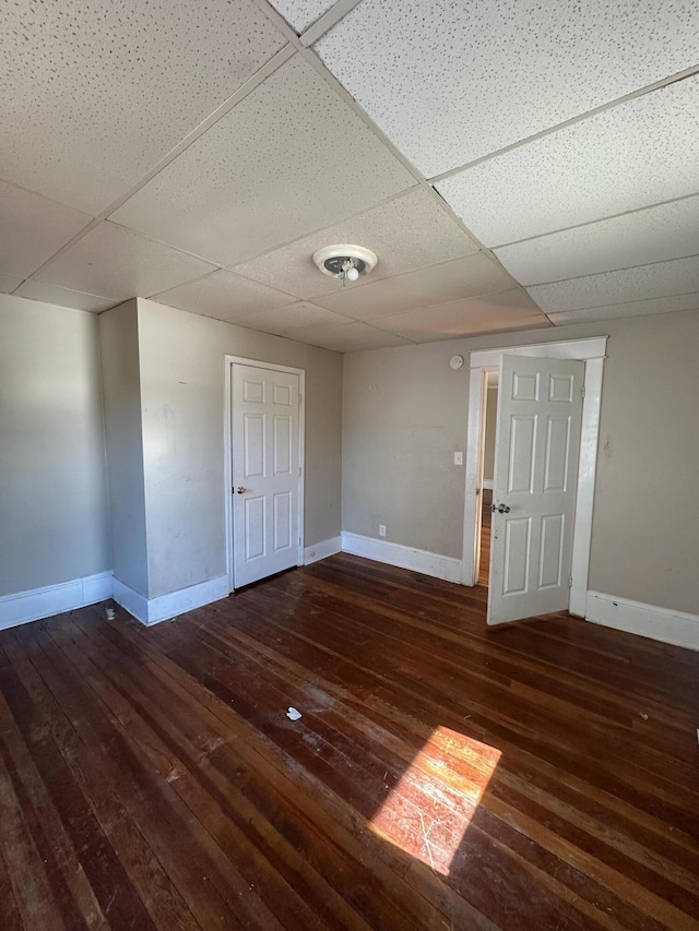 spare room with dark hardwood / wood-style flooring and a paneled ceiling