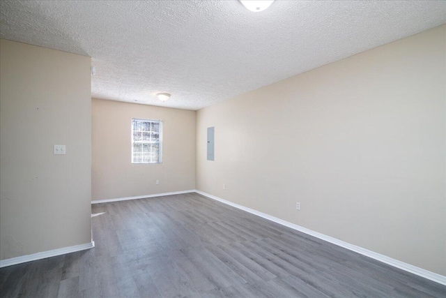 unfurnished room with a textured ceiling, electric panel, and dark hardwood / wood-style floors