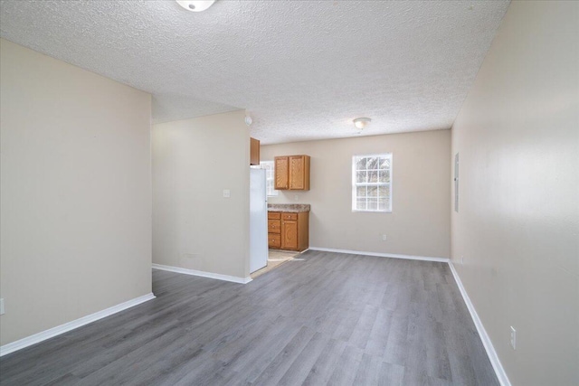 unfurnished living room featuring a textured ceiling and dark hardwood / wood-style flooring