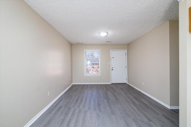 unfurnished room with a textured ceiling and dark hardwood / wood-style floors