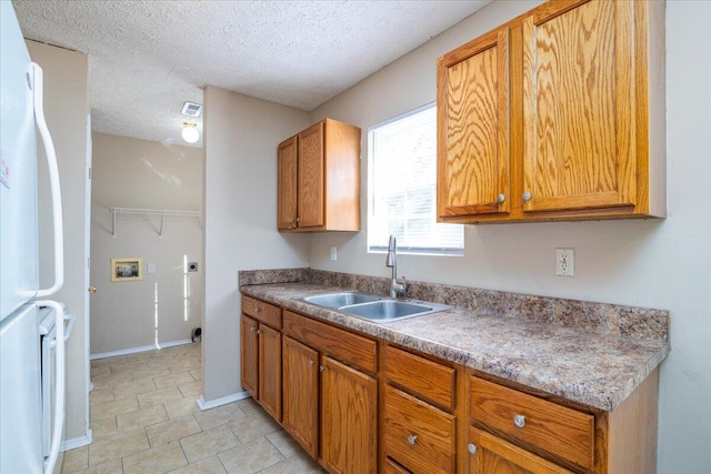 kitchen featuring sink, white refrigerator, and a textured ceiling