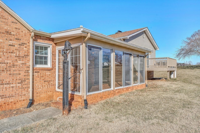 view of home's exterior featuring a wooden deck, a sunroom, and a lawn