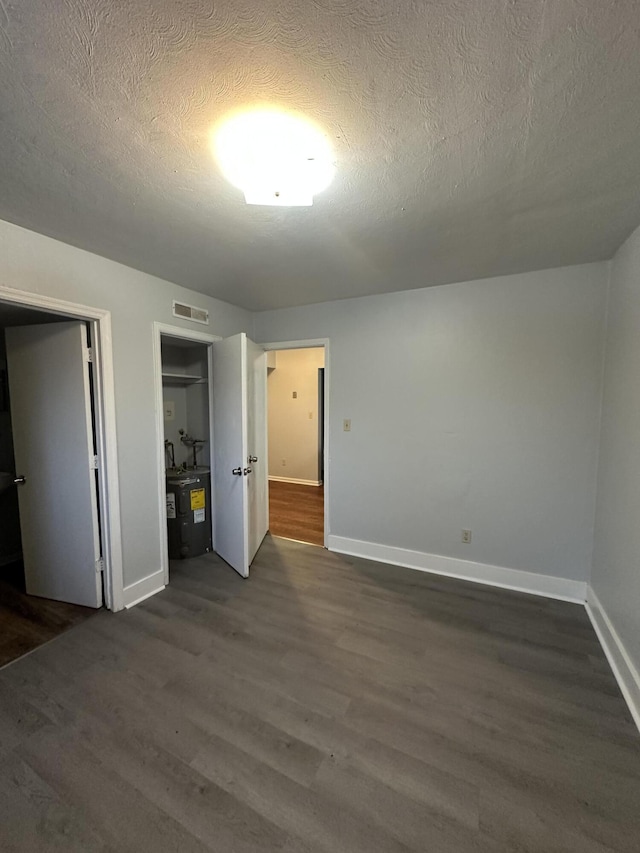 unfurnished bedroom with dark wood-type flooring and a textured ceiling