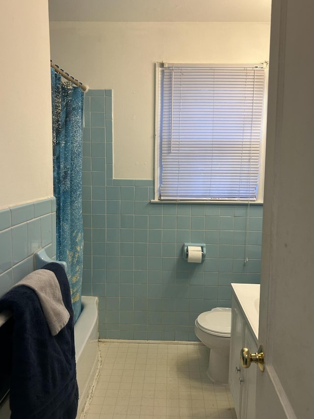 full bathroom with tile patterned floors, toilet, tile walls, vanity, and shower / bath combination with curtain