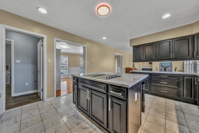 kitchen featuring light stone countertops, a textured ceiling, a kitchen island, black electric stovetop, and light tile patterned floors