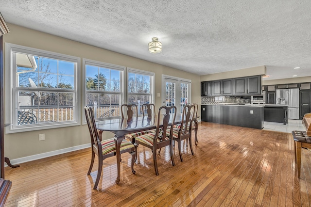 dining room with light wood-type flooring and a textured ceiling