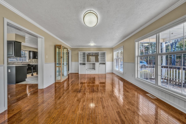 interior space with hardwood / wood-style flooring, a textured ceiling, and ornamental molding