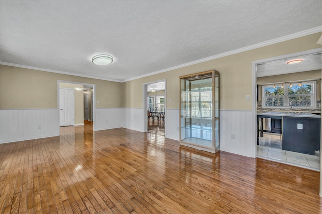 empty room featuring a textured ceiling, crown molding, and hardwood / wood-style floors