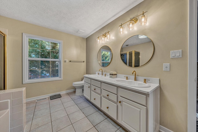 bathroom with a textured ceiling, toilet, tile patterned flooring, and vanity