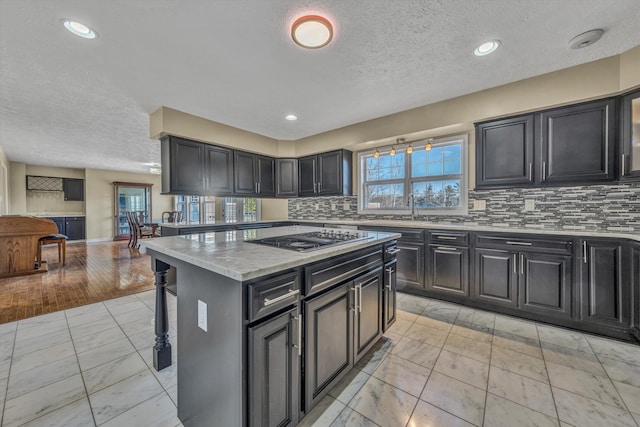 kitchen featuring tasteful backsplash, stainless steel gas stovetop, a kitchen island, light stone countertops, and a kitchen breakfast bar