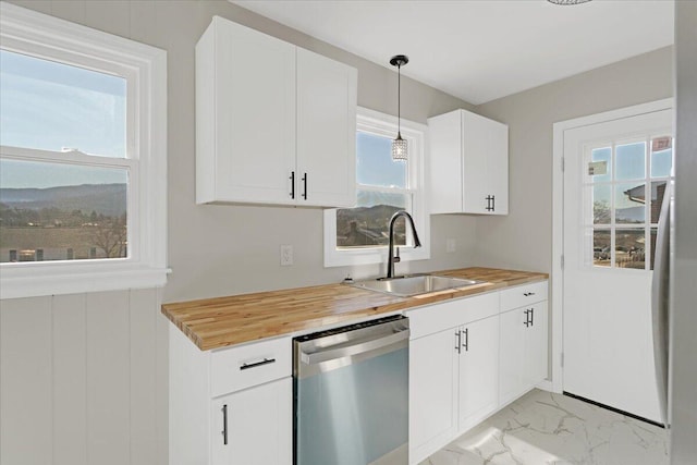 kitchen featuring sink, butcher block countertops, white cabinetry, dishwasher, and pendant lighting