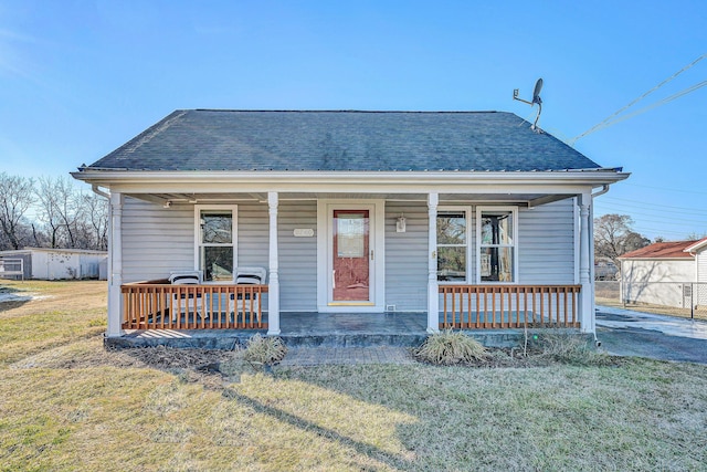 bungalow featuring covered porch and a front yard