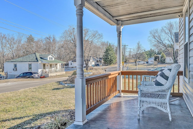 wooden terrace featuring a lawn and a porch