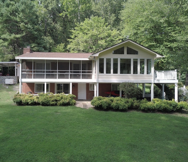 rear view of property featuring a yard and a sunroom