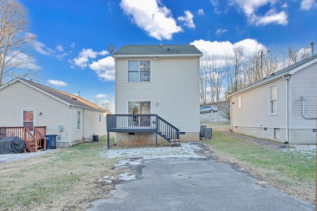 back of property featuring a deck, a lawn, and central AC