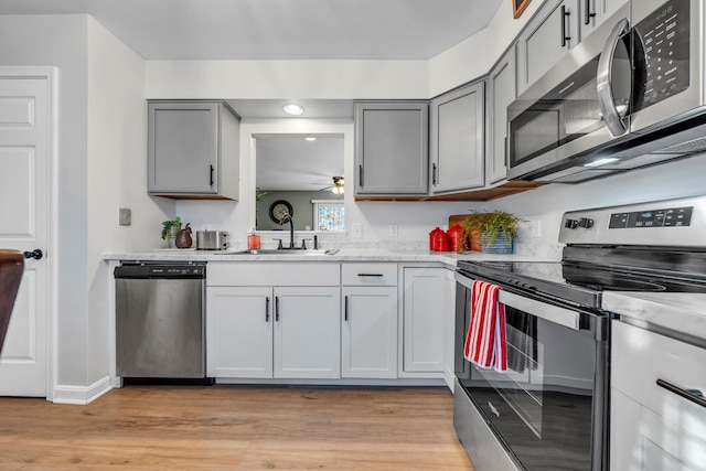 kitchen featuring light wood-type flooring, sink, gray cabinets, and stainless steel appliances